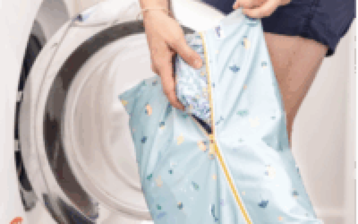 blue wetbag being held and put into a washing machine.